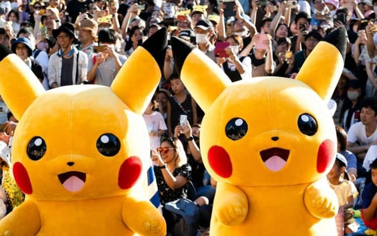 Dos botargas gigantes de Pikachu saludan alegremente a una multitud entusiasmada durante una celebración del Pokémon Day en Japón