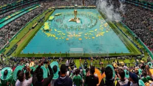 Vista de un estadio de la Copa del Mundo 2026 completamente lleno con miles de aficionados, banderas y una pantalla gigante que ilustra el impacto global y los récords de audiencia de las transmisiones.