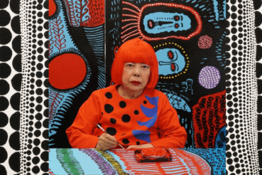 Yayoi Kusama pintando frente a uno de sus característicos fondos llenos de lunares y colores vibrantes