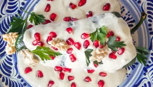 Chile en nogada tradicional bañado en nogada blanca con granada roja, servido en un restaurante reconocido de Puebla durante la temporada 2026