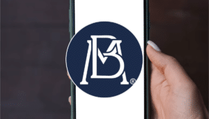 Manos sosteniendo un teléfono celular con una aplicación bancaria abierta en la pantalla, lista para hacer una transferencia