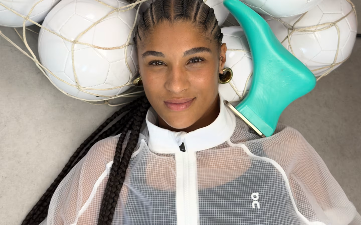 Sydney Schertenleib con chamarra blanca de On recostada junto a una red de balones de fútbol